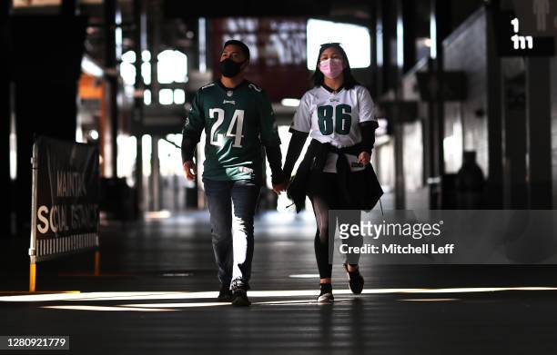 Philadelphia Eagles fans wear face masks as they walk along an empty concourse at Lincoln Financial Field for a game against the Baltimore Ravens on...