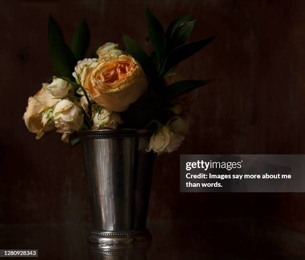 a silver vase displays a wilted rose bouquet. still life. - metal flower arrangement stock pictures, royalty-free photos & images