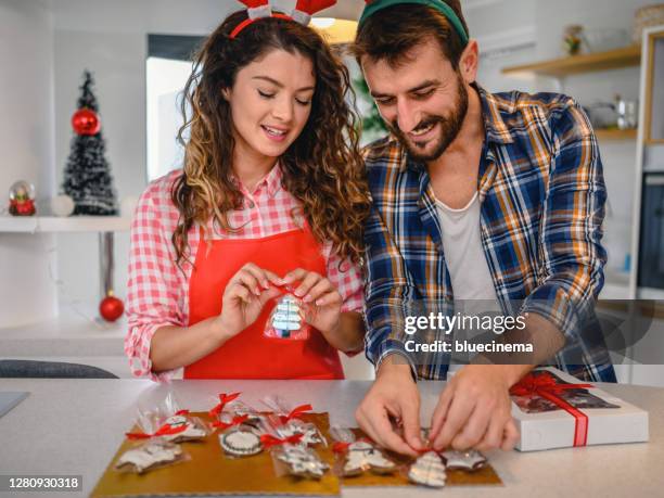 couples empaquetant des biscuits de pain d’épice de noël - christmas font photos et images de collection