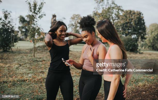 three joggers stop to receive some good news on a mobile phone - incoraggiamento foto e immagini stock