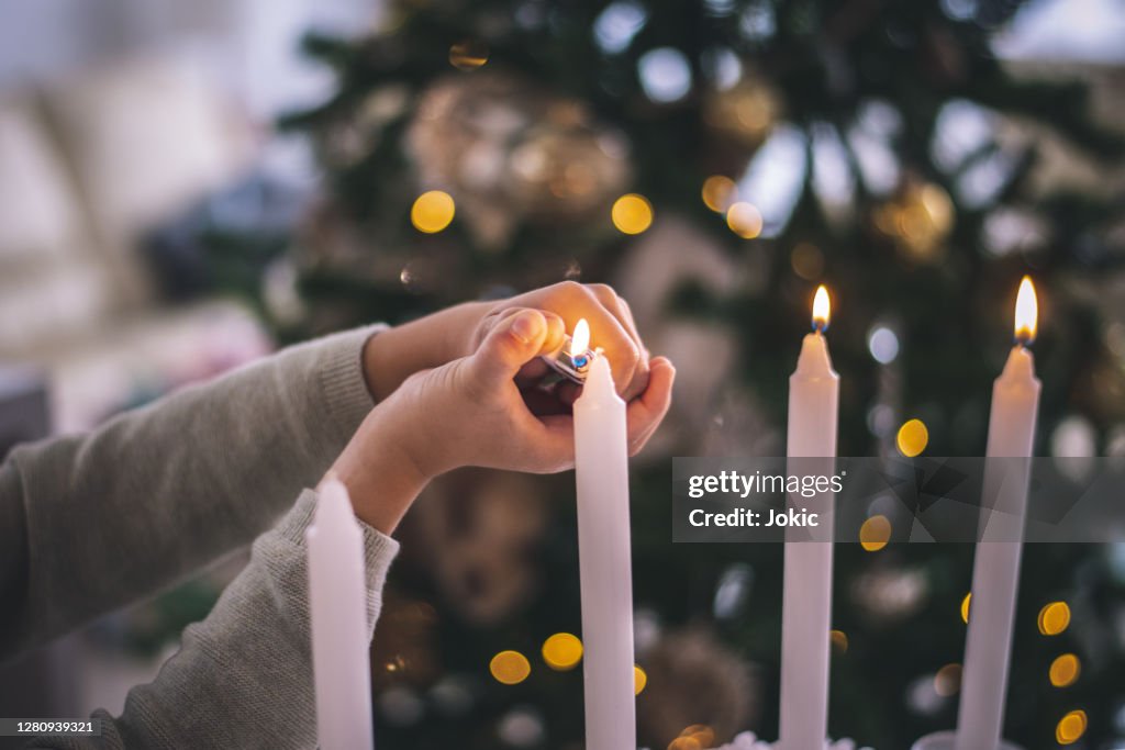 Christmas detail, lightning candles. Kid enjoy in living room during Christmas Celebration, Cheerful Christmas time