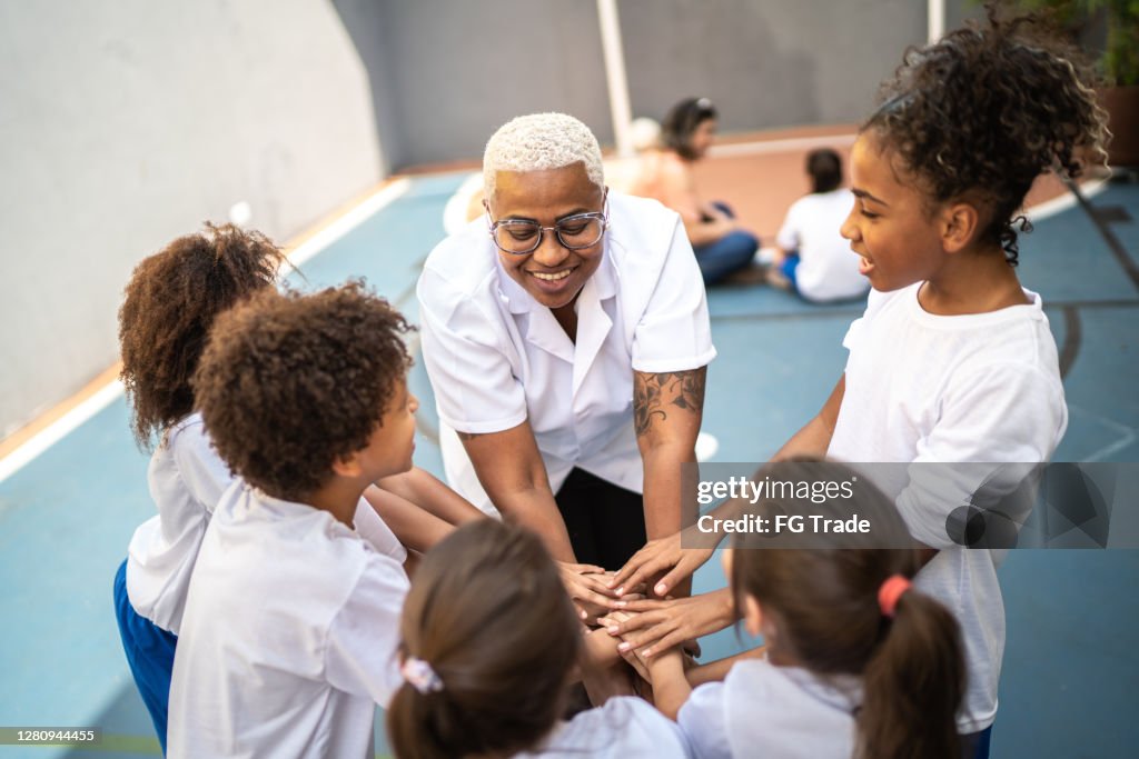 Teacher and students - teamwork huddling before sports game in school