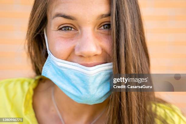 smiling young woman wearing protective face mask below her nose - nose mask stock pictures, royalty-free photos & images