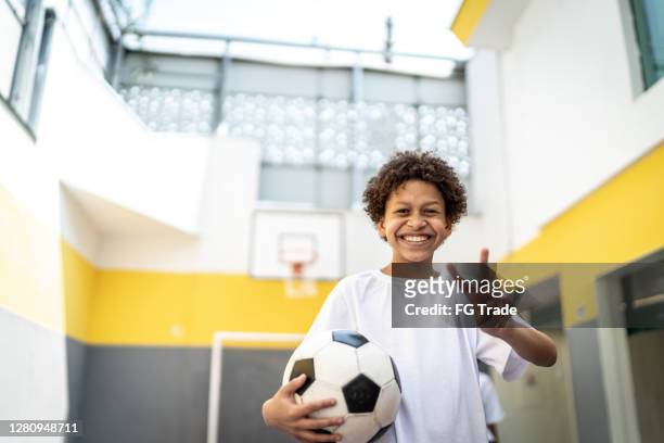 porträtt av en lycklig pojke som håller en fotboll och gör fred tecken - brazilian playing football bildbanksfoton och bilder