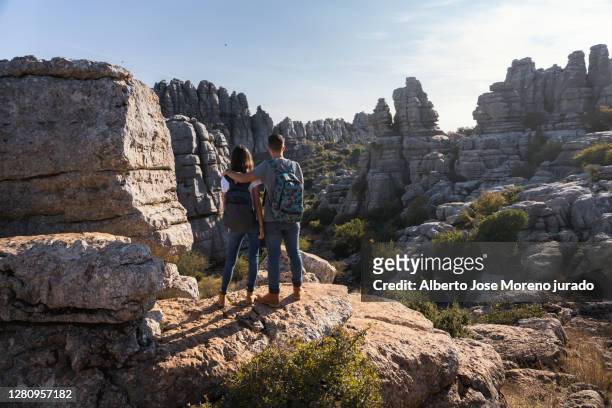 couple of mountaineers looking at the mountainous landscape - paraje natural torcal de antequera stock-fotos und bilder
