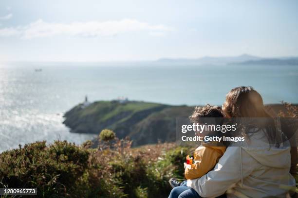 a woman and her son overlooking the ocean on a hill. - irish family stock pictures, royalty-free photos & images