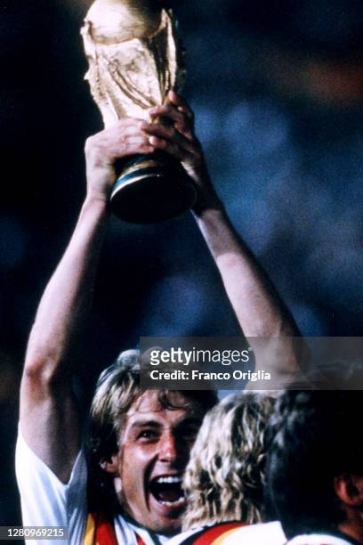 Jürgen Klinsmann of West Germany celebrates with the trophy after winning the 1990 FIFA World Cup Final between West Germany and Argentina at the...