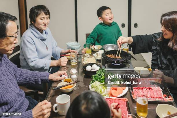 japanische mulit generation familie essen sukiyaki zum abendessen im wohnzimmer - sukiyaki stock-fotos und bilder