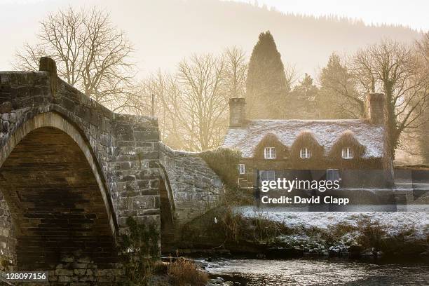the famous cottage standing at llanrwst bridge that spans the afon conwy river, llanrwst, north wales, britain, uk - かやぶき屋根 ストックフォトと画像