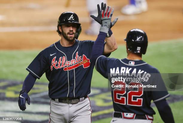 Dansby Swanson of the Atlanta Braves is congratulated by Nick Markakis after hitting a solo home run against the Los Angeles Dodgers during the...
