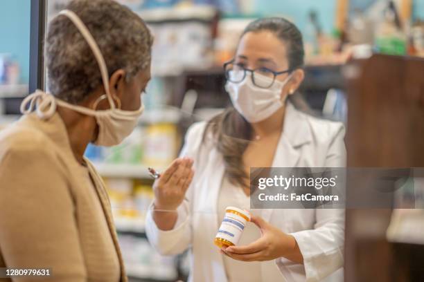 female pharmacist speaking with customer - pharmacist and patient stock pictures, royalty-free photos & images