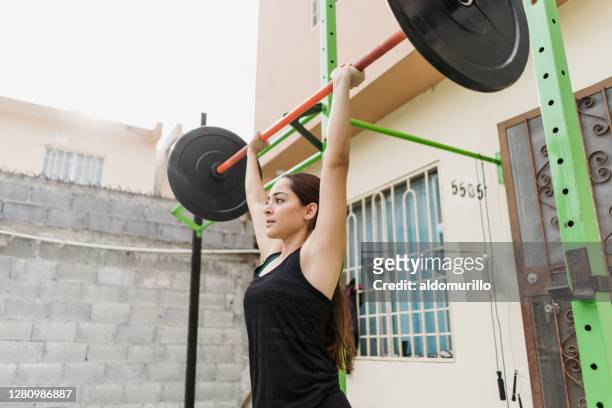 latijnse sportswoman die staaf met gewichten thuis opheft - nosotroscollection stockfoto's en -beelden