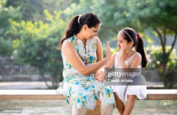 mother and daughter giving high five to each other at park - indian mother and child stock pictures, royalty-free photos & images