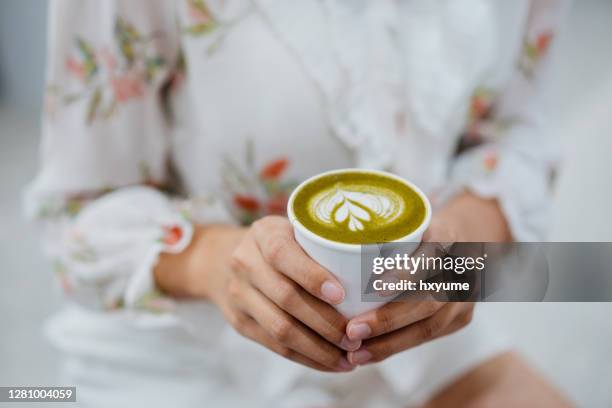 eine asiatische chinesin hält eine tasse matcha latte - matcha stock-fotos und bilder