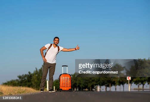 Young traveller hitchhiking on the roadside