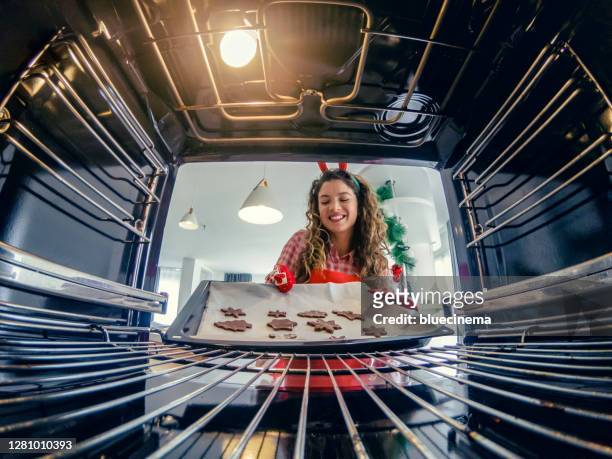 happy woman putting christmas cookies in the oven - baking tray stock pictures, royalty-free photos & images