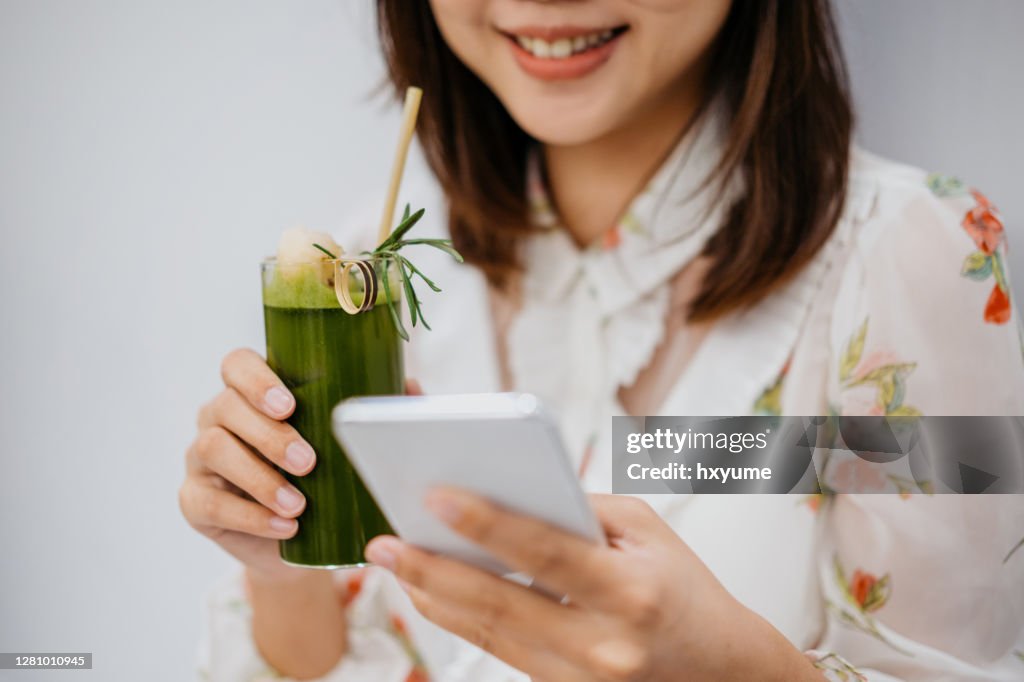 微笑的亞裔華人女性在咖啡館里使用智能手機。