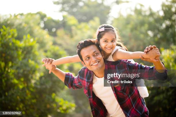 father and daughter enjoying piggyback ride - indian ethnicity family stock pictures, royalty-free photos & images