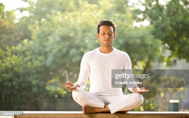 uomo che medita in posizione loto al parco - meditation sitting foto e immagini stock