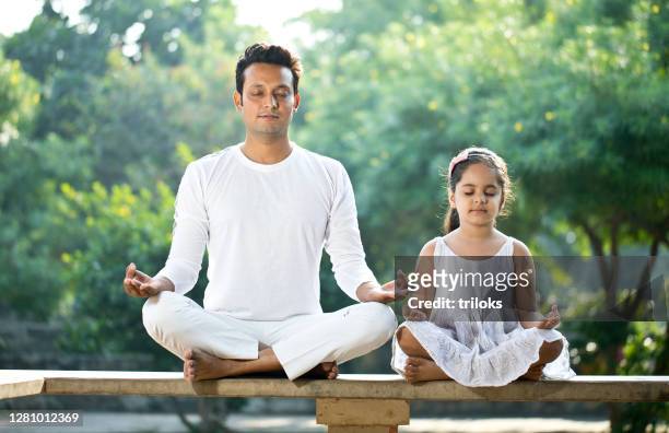 father and daughter meditating outdoors at park - yoga stock pictures, royalty-free photos & images
