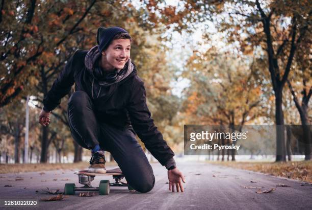 young man rides fast a skateboard on the road - longboard surfing stock pictures, royalty-free photos & images