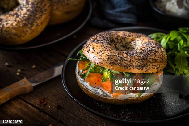poppy seed bagel with cheese cream, smoked salmon and arugula - pãozinho em forma de anel imagens e fotografias de stock