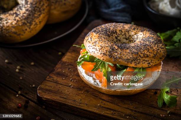 poppy seed bagel with cheese cream, smoked salmon and arugula - cream cheese stock pictures, royalty-free photos & images