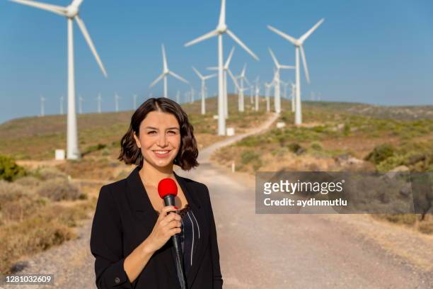 female journalist presents live broadcast on wind turbines - newscaster stock pictures, royalty-free photos & images