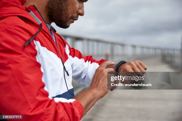 african-american man tapping fitness tracker after run by river bridge - running man heartbeat stock pictures, royalty-free photos & images