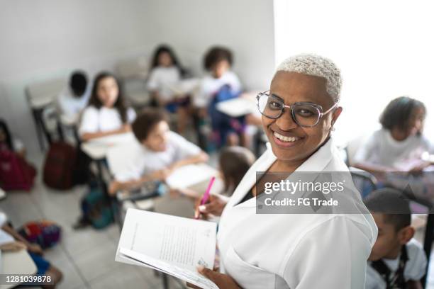 porträt eines stolzen lehrers im klassenzimmer in der schule - staatliche schule stock-fotos und bilder