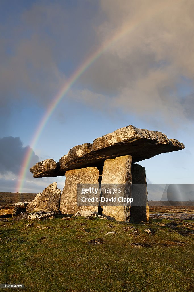 Dawn rainbow at the Poulnabrone Dolmen, a burial chamber or dolmen, situated on the Burren, County Clare, Republic of Ireland