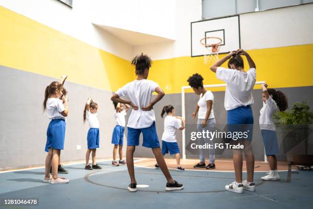 professor de atividade física estica braços com alunos na escola - physical education - fotografias e filmes do acervo