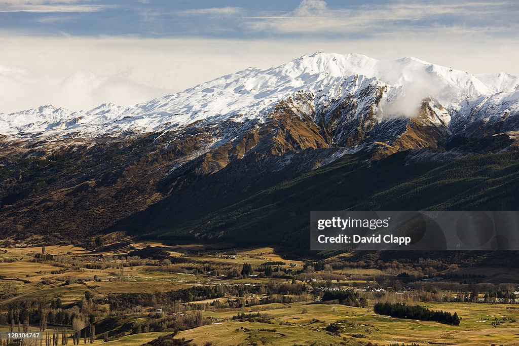End of Crown Mountain Range with Arrowtown, an old gold mining community, nestled in valley, South Island, New Zealand