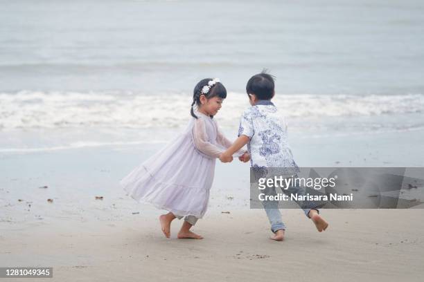 brother and sister enjoy dancing on the beach with happiness. childhood concept. - pattaya fotografías e imágenes de stock