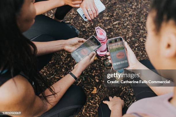 overhead view of female joggers looking at a fitness app on their smart phones - pedometer stock pictures, royalty-free photos & images