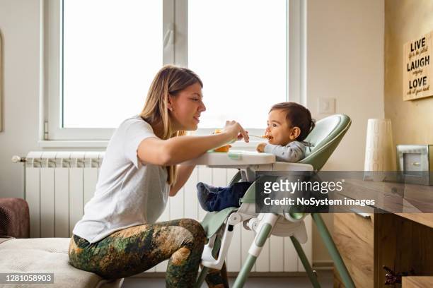 family life. mother feeding her baby at home. - baby eating food imagens e fotografias de stock