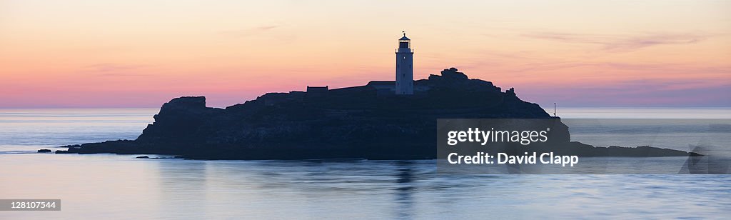 Last light at Godrevy Lighthouse, viewed through a gap in between two rock faces at Godrevy Point, Cornwall, England, United Kingdom, UK, Europe