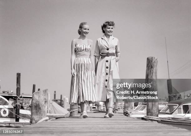 1940s 1950s Two Smiling Women Sisters Wearing Stylish Summer Dresses Walking Along Wooden Boat Dock At Seashore