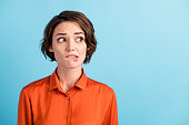 Closeup photo of sad depressed displeased lady horrified facial expression made huge big mistake feel guilty look side empty space bite lips wear orange shirt isolated blue color background