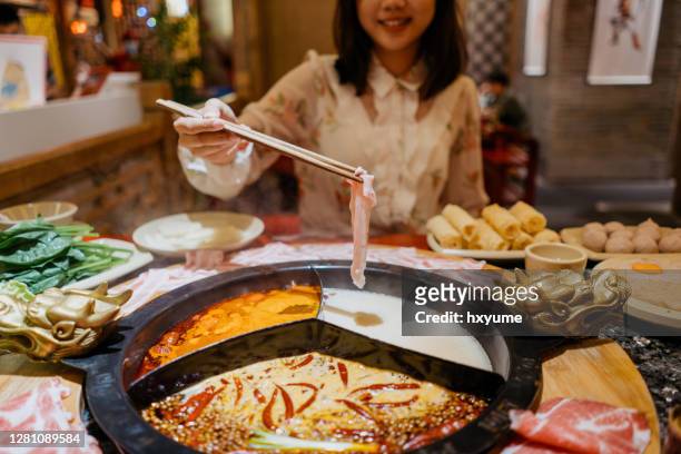 een aziatische chinese vrouw die een varkensvleesplakje met hete potsoep kookt - szechuan cuisine stockfoto's en -beelden