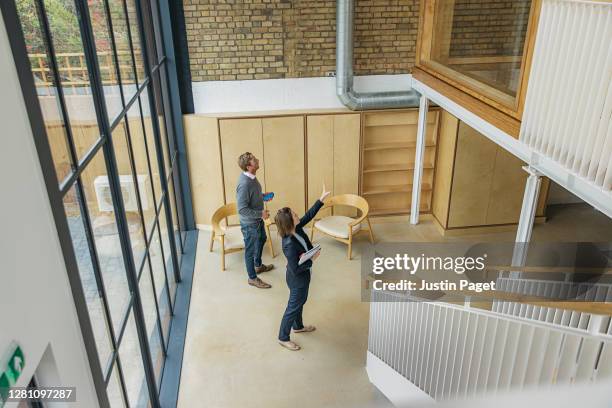 female property agent showing man around empty office space - commercial property imagens e fotografias de stock