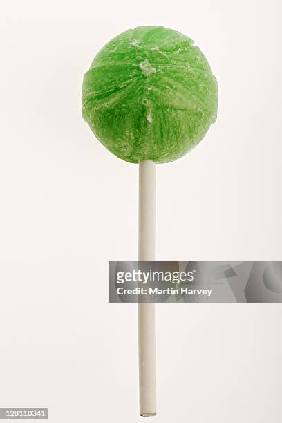 close-up of a bright green lollipop. studio shot against a white background. - zuignap stockfoto's en -beelden