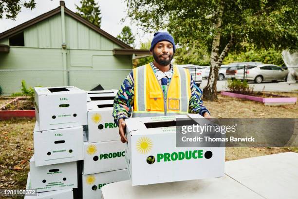 portrait of volunteer at community center giving away csa boxes - charity and relief work stock pictures, royalty-free photos & images