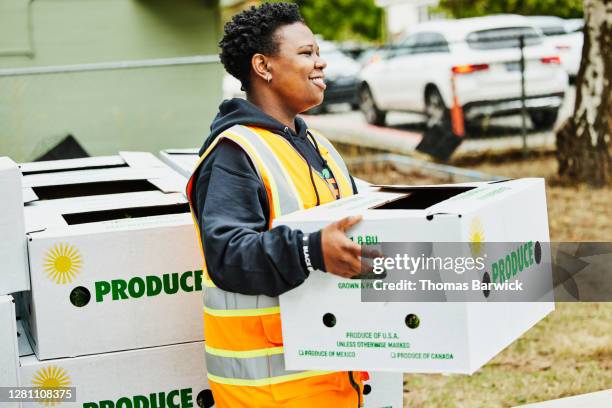 smiling volunteer holding csa box at community center - help single word stock-fotos und bilder