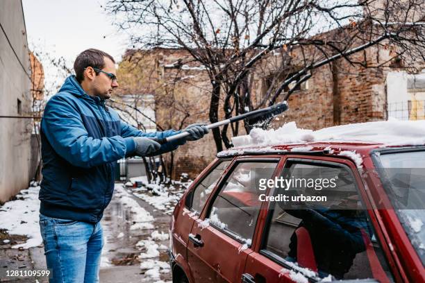 man cleaning snow off her car - snow melting on car stock pictures, royalty-free photos & images
