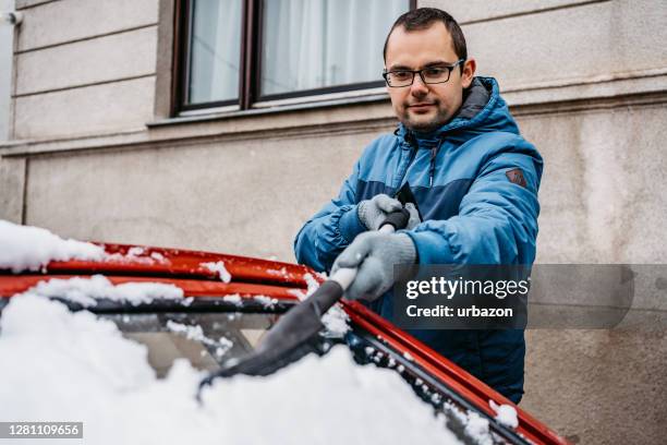 man cleaning snow off her car - snow melting on car stock pictures, royalty-free photos & images