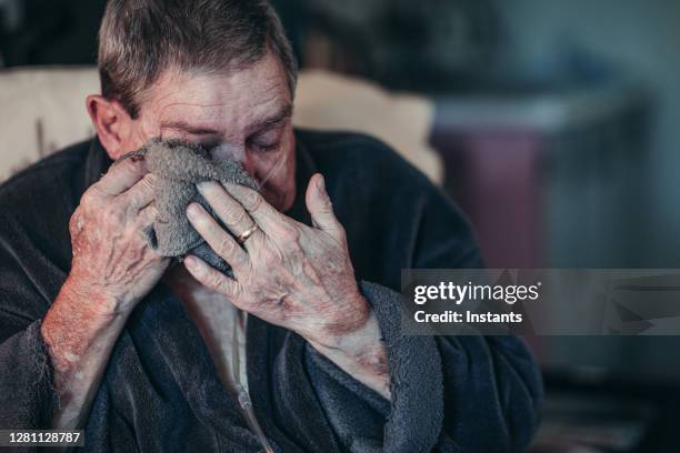 ein älterer mann wischt sich die augenlider mit einem gesichtstuch, nachdem er seine augentropfenbehandlung in saugen lässt. - washcloth stock-fotos und bilder