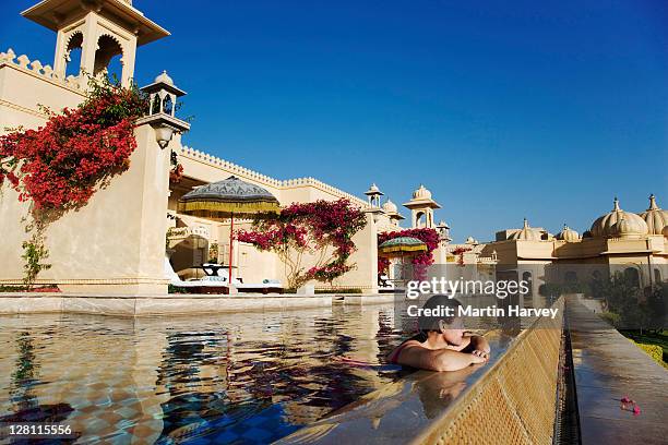 tourist enjoying a swim in the semi private pool of the deluxe rooms at the ultra luxurious udaivilã¢s oberoi hotel. udaipur. this hotel has been voted the 3rd best hotel in the world by travel and leisure magazine. india. (mr) - india tourism stock pictures, royalty-free photos & images