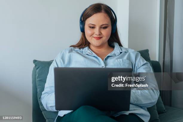 happy plus size businesswoman with headphones working in a relaxed atmosphere of a modern it company - business woman blue stock pictures, royalty-free photos & images