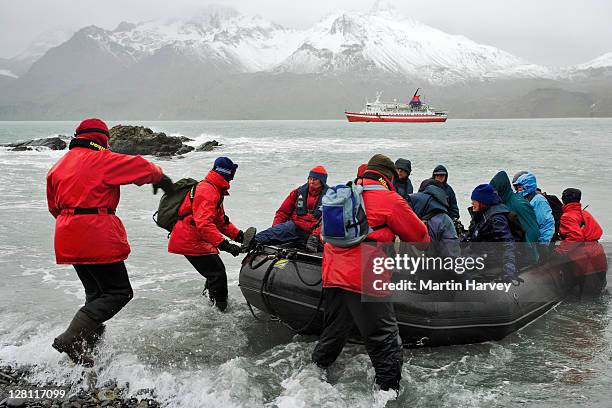 crew helping tourists ashore from zodiac. in background g.a.p adventures ms explorer cruise ship. antarctica (pr: property released) - antarctica people stock pictures, royalty-free photos & images